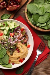 Photo of Delicious vegan bowl with cucumbers, spinach and hummus on wooden table, flat lay