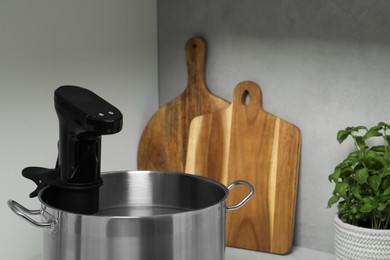 Pot with sous vide cooker in kitchen, closeup. Thermal immersion circulator