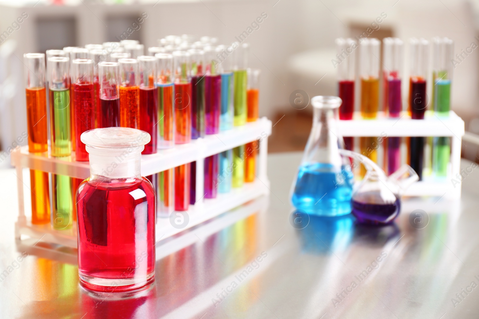 Photo of Laboratory glassware with color liquids on table. Solution chemistry