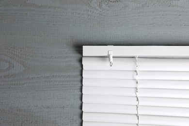 Photo of Stylish horizontal window blinds on grey wooden table, top view. Space for text