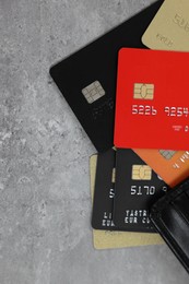 Photo of Pile of different credit cards on grey table, top view