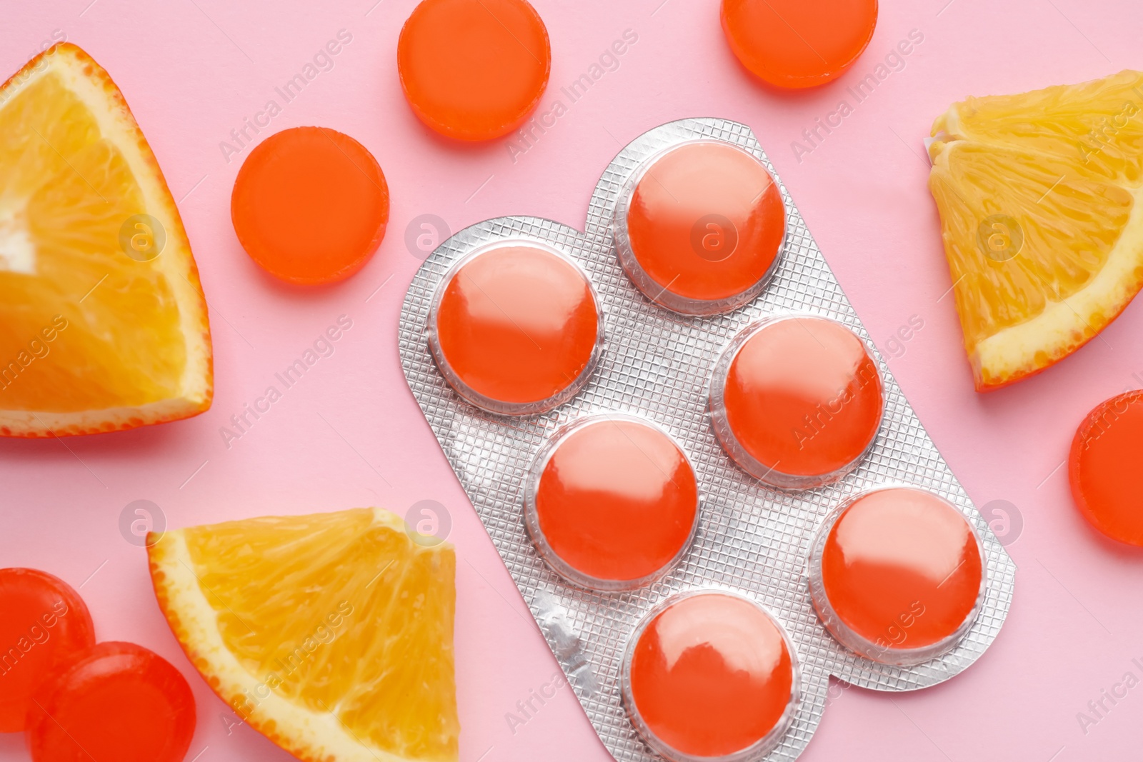 Photo of Many orange cough drops on pink background, flat lay