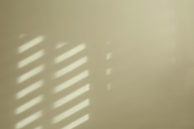 Light and shadow from window on beige wall indoors