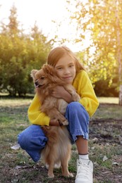 Photo of Little girl with her cute dog in park. Autumn walk