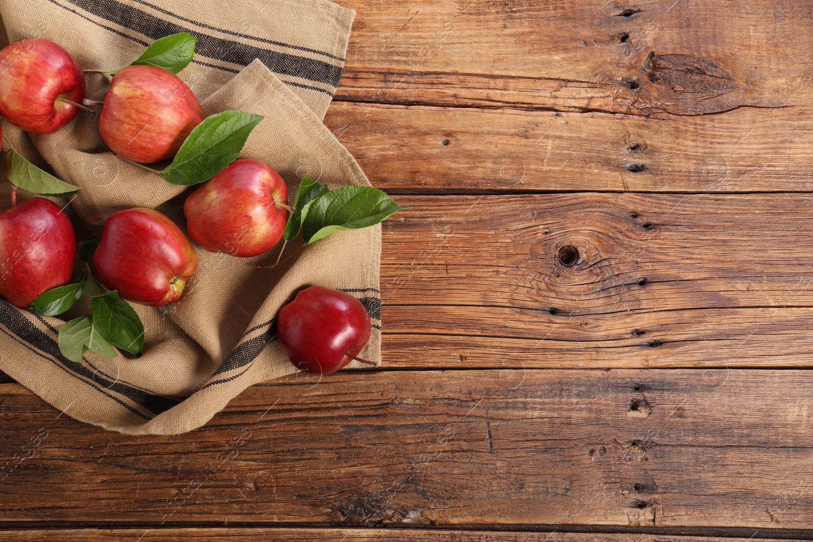 Photo of Ripe red apples with leaves on wooden table, flat lay. Space for text