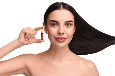 Beautiful young woman with long healthy hair holding ampoule on white background