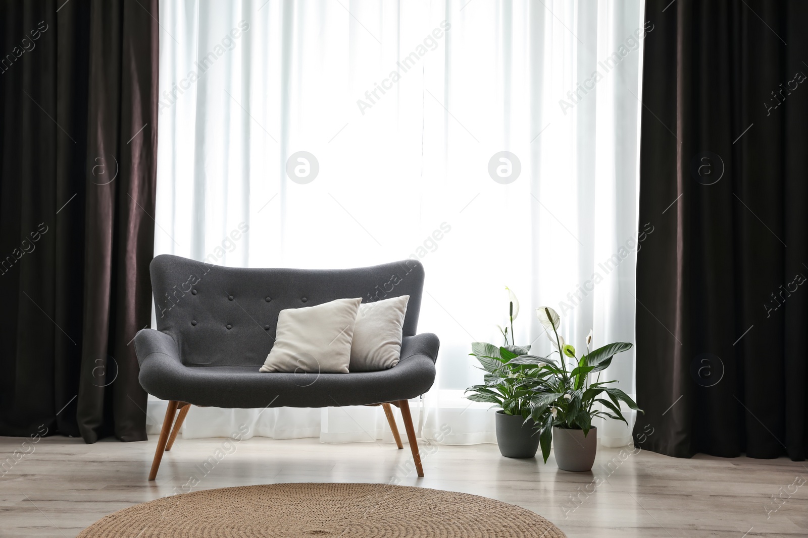 Photo of Comfortable sofa near window with elegant curtains in room