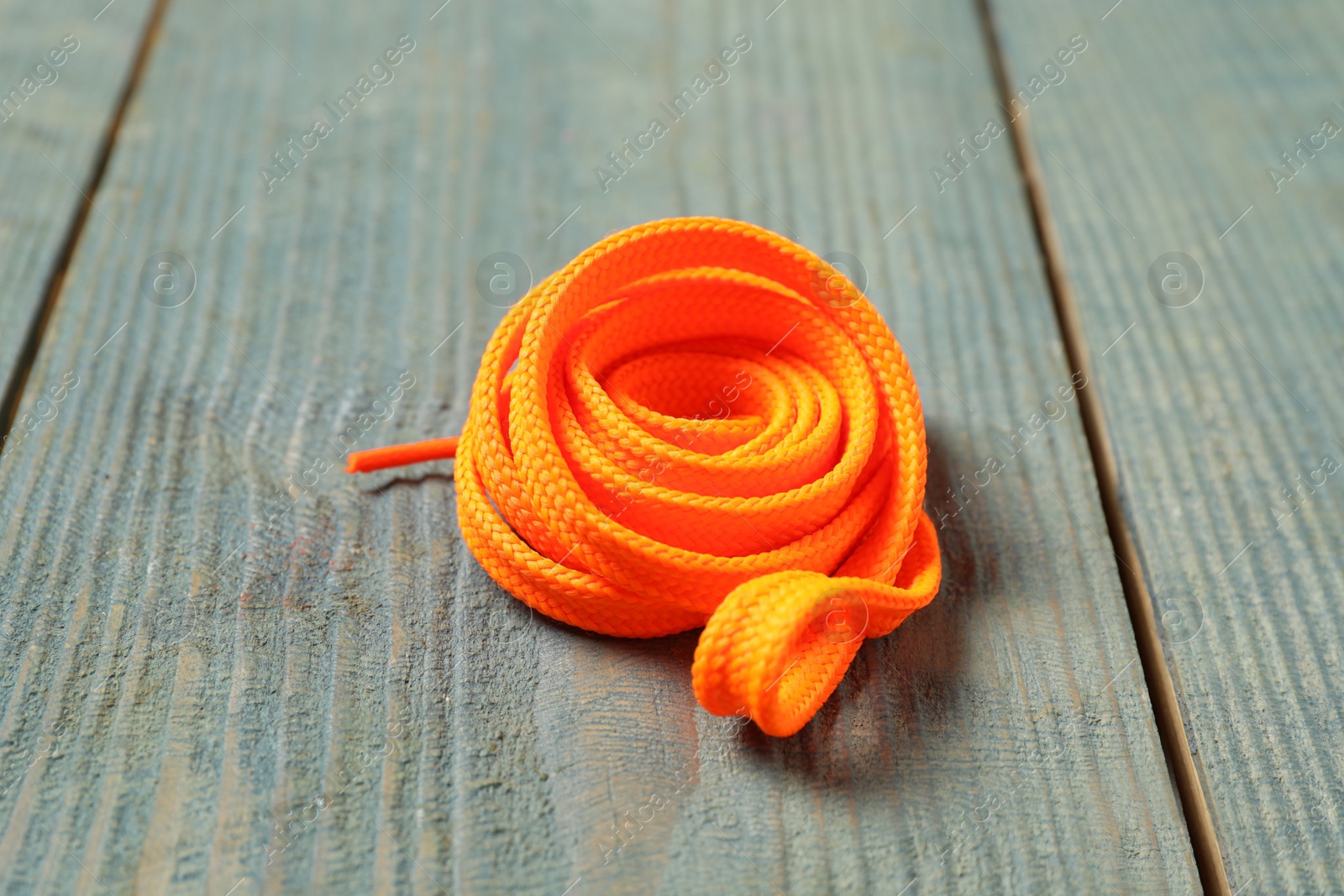 Photo of Orange shoelace on light blue wooden background
