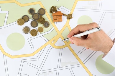 Cartographer with house key and money drawing cadastral map, closeup