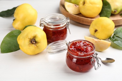 Photo of Delicious quince jam and fruits on white wooden table