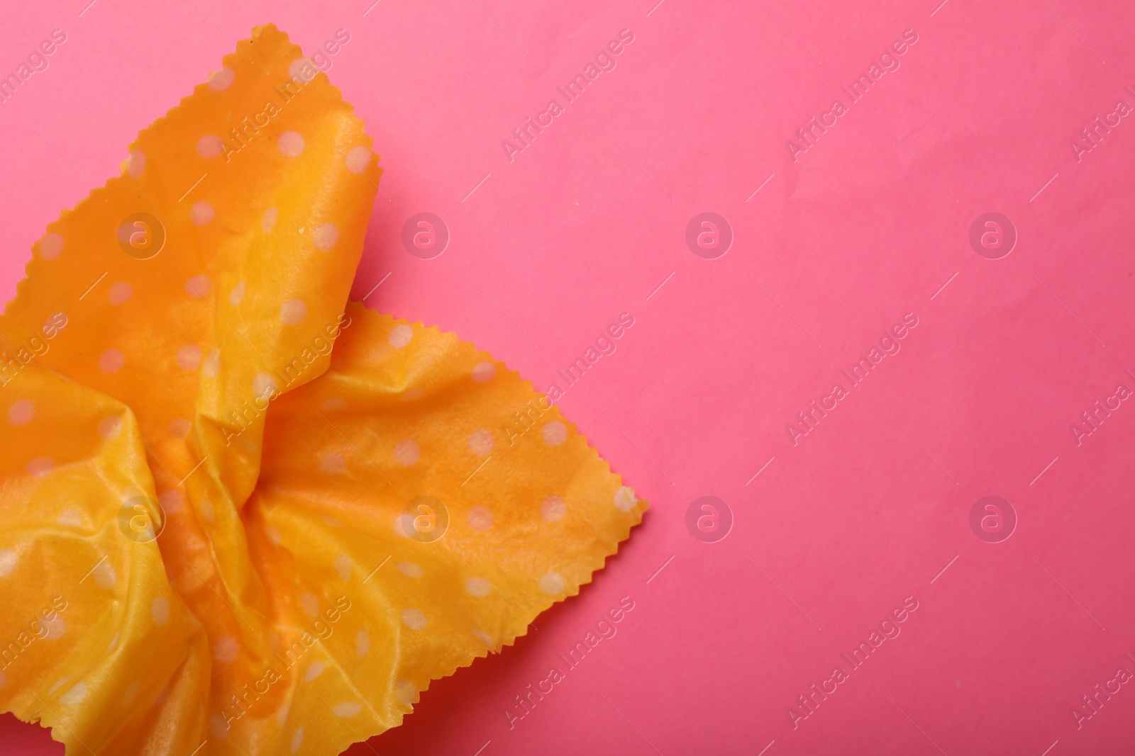 Photo of Crumpled beeswax food wrap on pink background, top view. Space for text