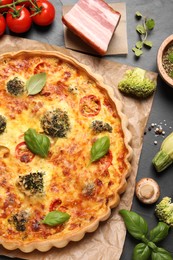 Photo of Delicious homemade quiche and products on black table, flat lay