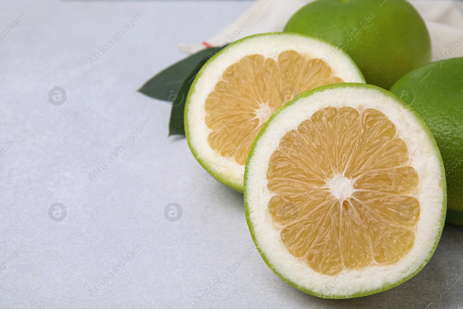 Photo of Whole and cut sweetie fruits on light table, closeup. Space for text