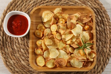 Tasty homemade parsnip chips with sauce on white wooden table, top view