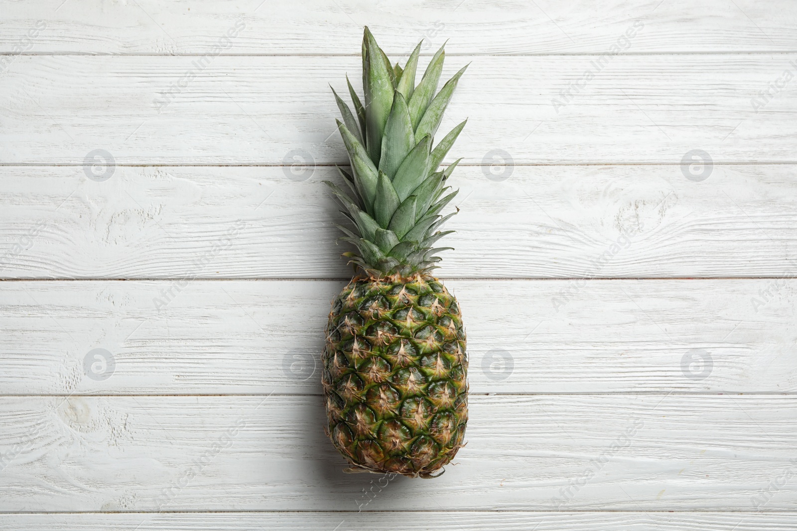 Photo of Fresh whole pineapple on white wooden background, top view