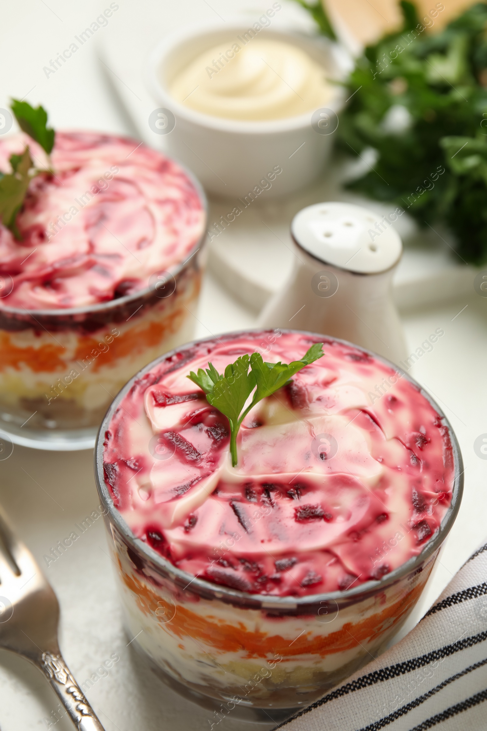 Photo of Herring under fur coat served on white table. Traditional russian salad