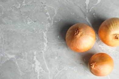 Photo of Ripe onions on grey table, flat lay with space for text