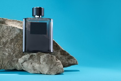 Stylish presentation of luxury men`s perfume on stones against light blue background