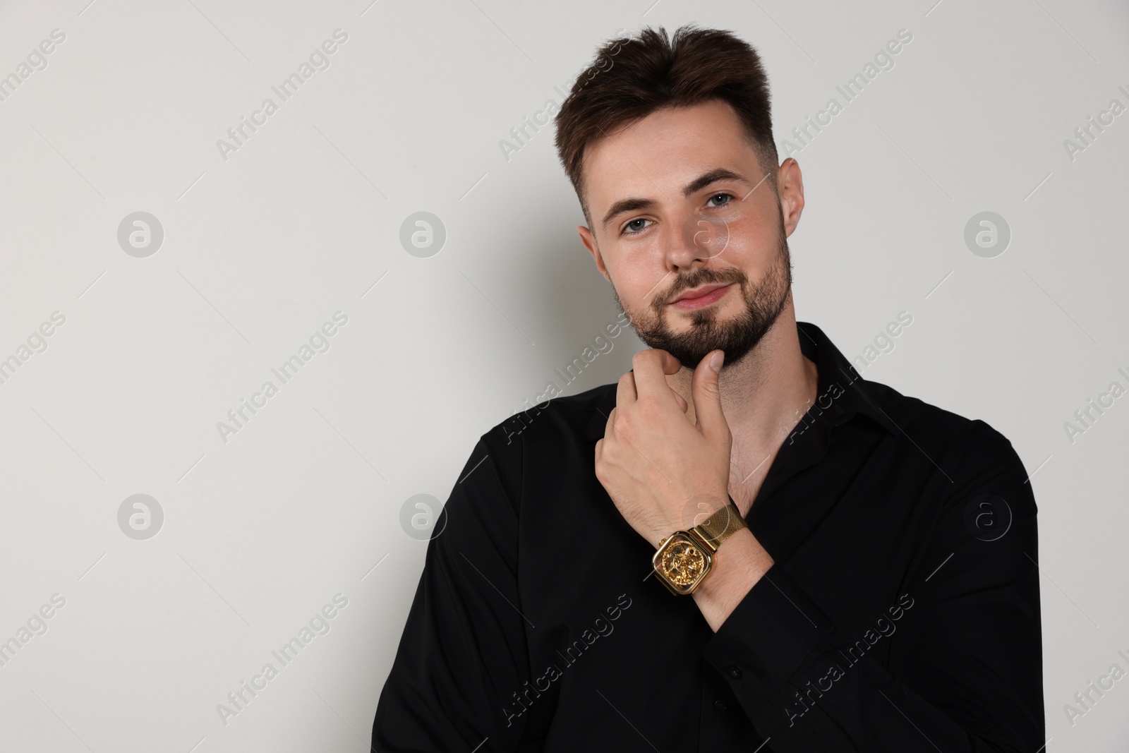 Photo of Handsome man in black shirt on light grey background, space for text