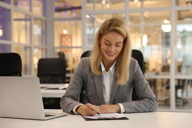 Smiling woman working at table in office. Lawyer, businesswoman, accountant or manager