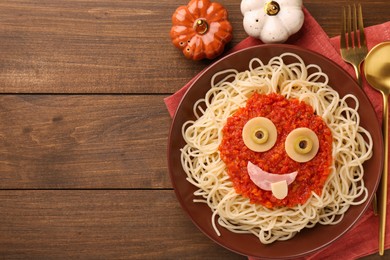 Plate with funny monster made of tasty pasta served on wooden table, flat lay with space for text. Halloween food