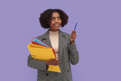 Photo of African American intern with folders and pen on purple background