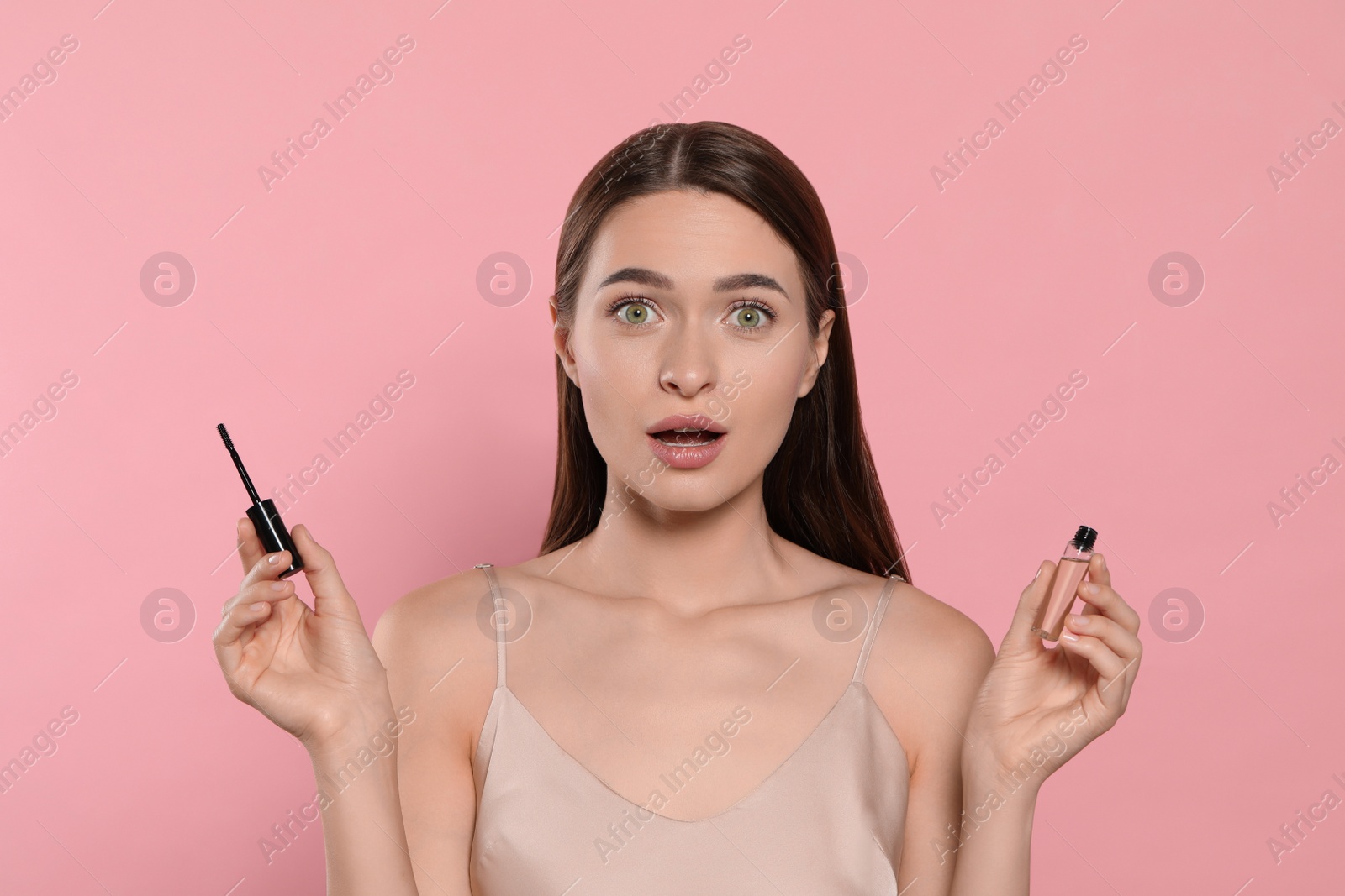 Photo of Emotional woman with eyelash oil on pink background