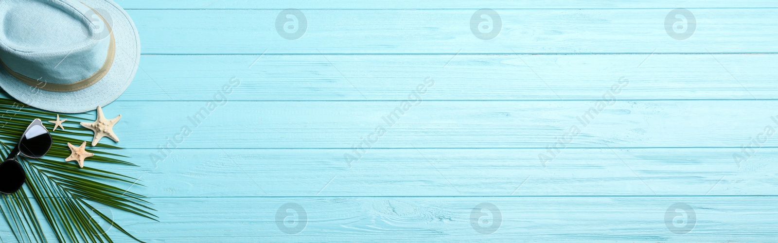 Photo of Beach accessories and space for text on light blue wooden background, flat lay. Banner design