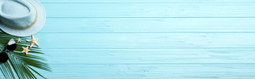 Photo of Beach accessories and space for text on light blue wooden background, flat lay. Banner design