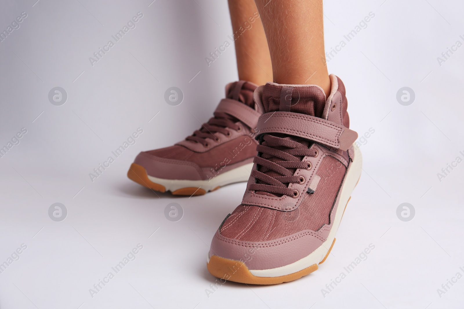 Photo of Girl wearing stylish sneakers on white background, closeup