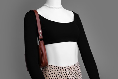 Photo of Female mannequin with necklace and bag dressed in stylish outfit on grey background
