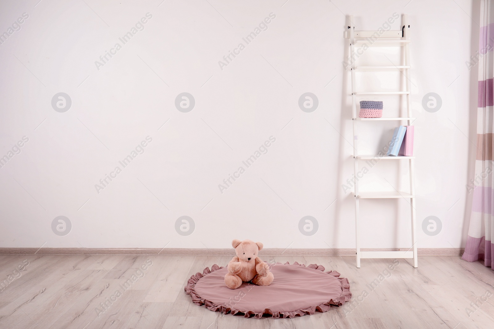 Photo of Teddy bear on floor and shelving unit near wall in child room. Space for text