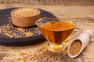 Photo of Jug of natural oil and mustard seeds on wooden table