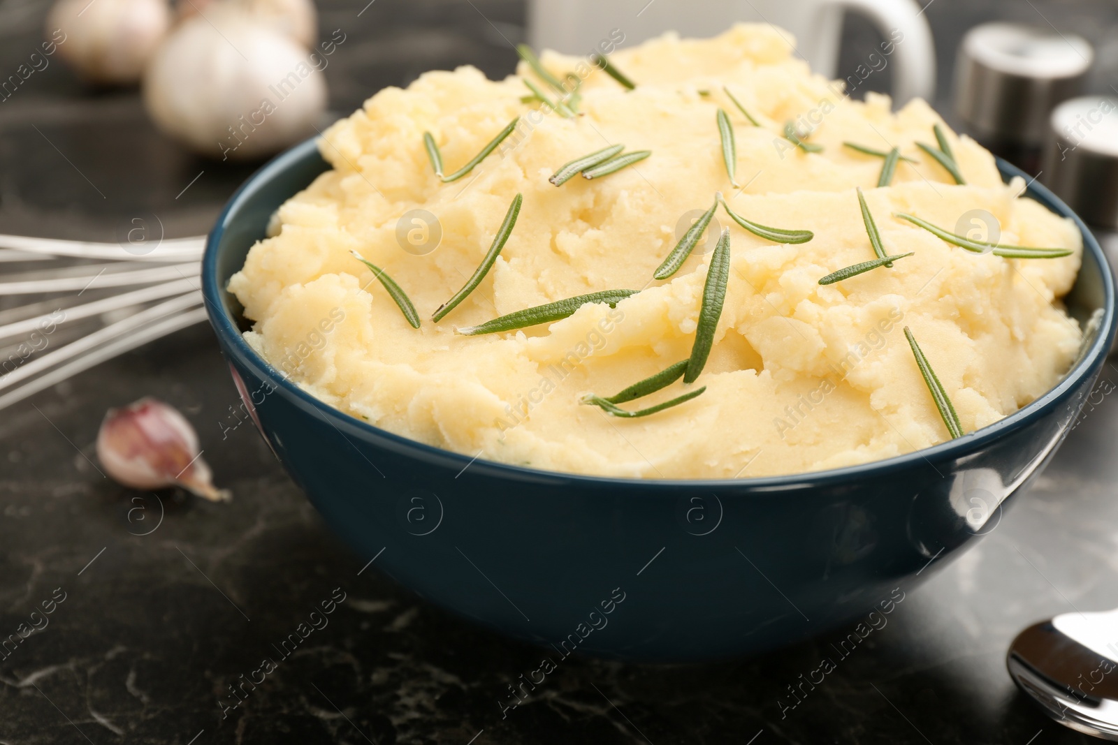 Photo of Bowl with tasty mashed potato on dark table