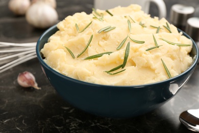 Photo of Bowl with tasty mashed potato on dark table