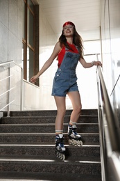 Photo of Beautiful young woman with roller skates on stairs outdoors