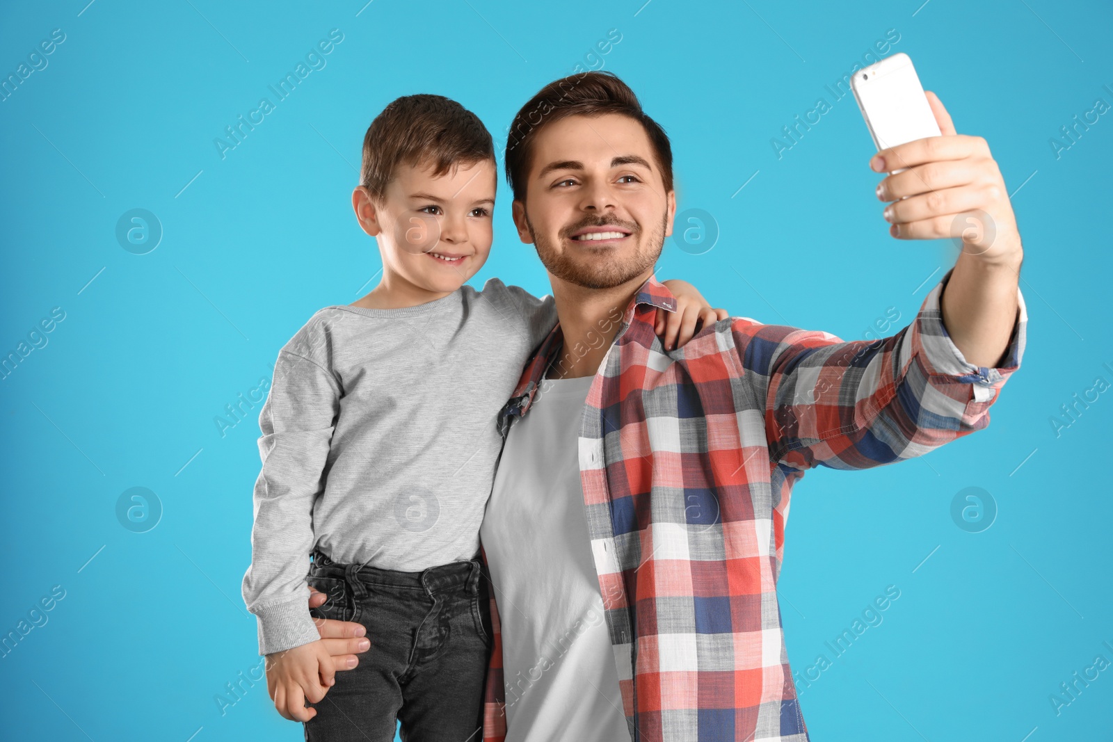 Photo of Dad and his son taking selfie on color background