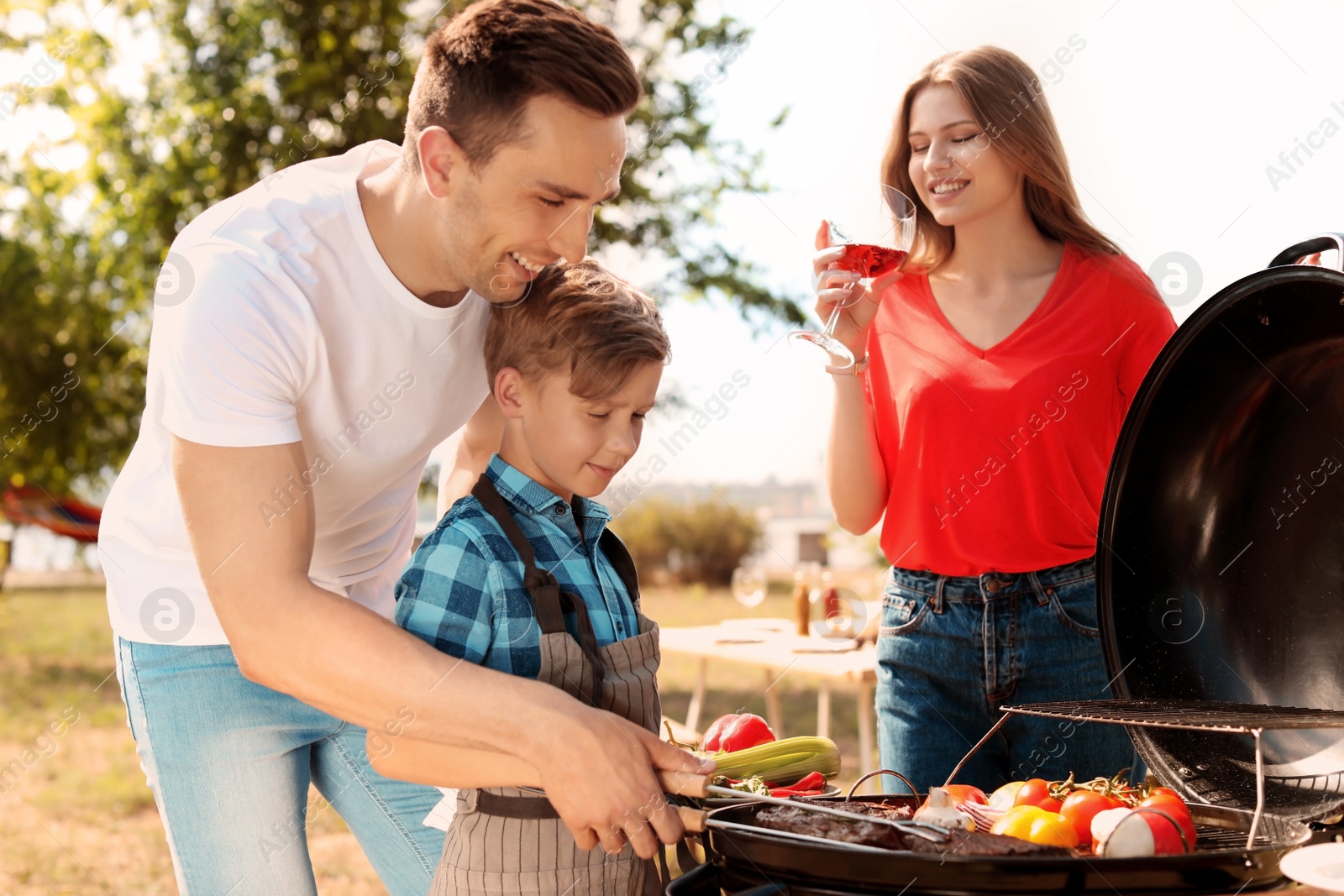 Photo of Happy family having barbecue with modern grill outdoors