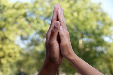 Photo of Woman and African American man giving high five outdoors, closeup