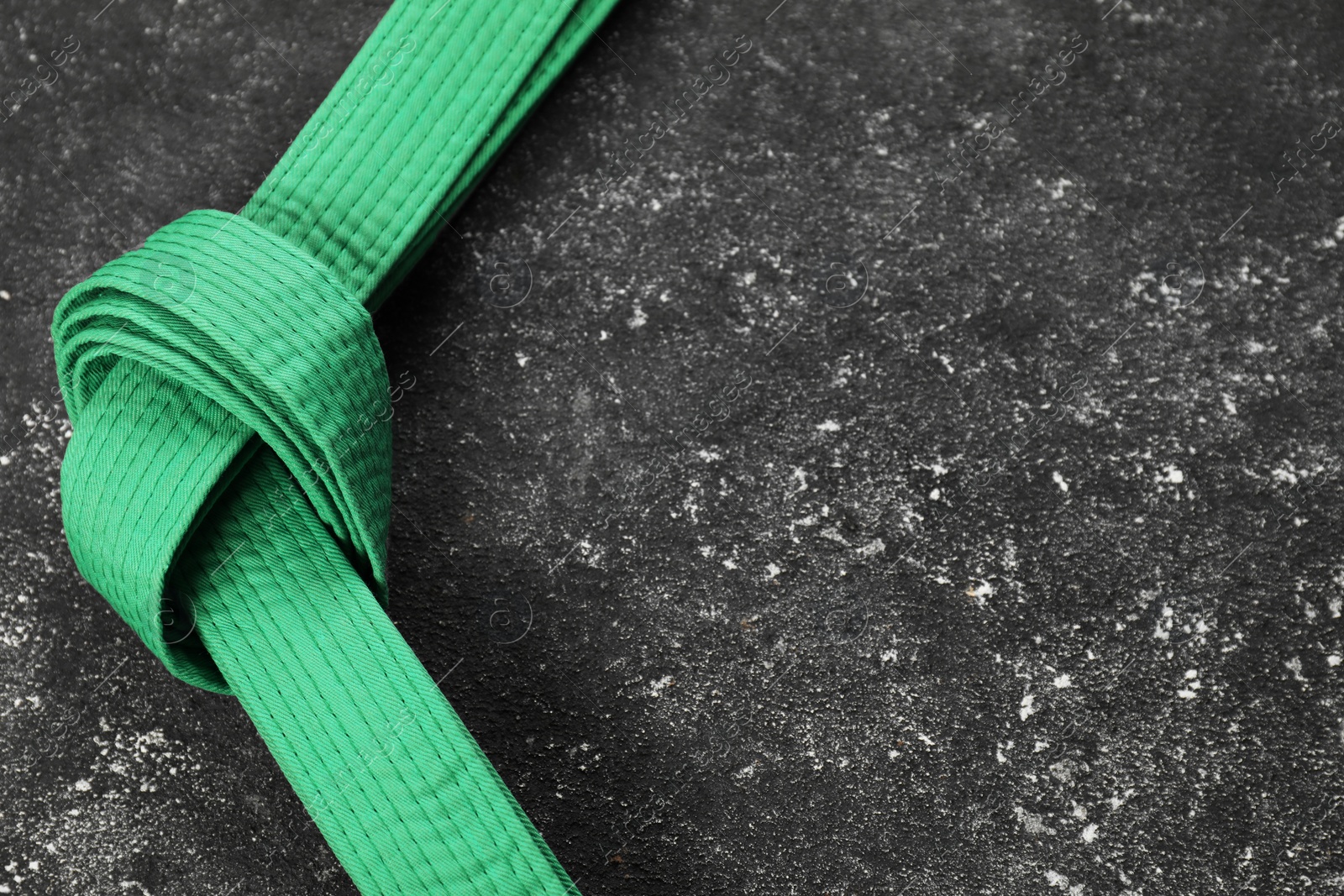 Photo of Green karate belt on gray textured background, space for text