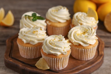 Photo of Delicious cupcakes with white cream and lemon zest on wooden table, closeup