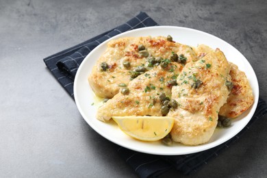 Photo of Delicious chicken piccata with herbs on grey table. Space for text