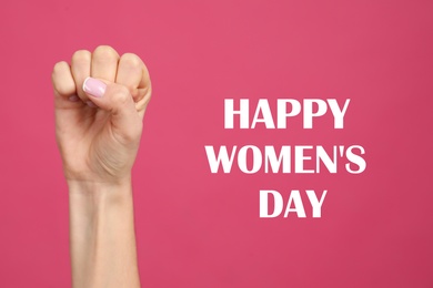 Woman showing fist as girl power symbol on pink background, closeup. Happy Women's Day