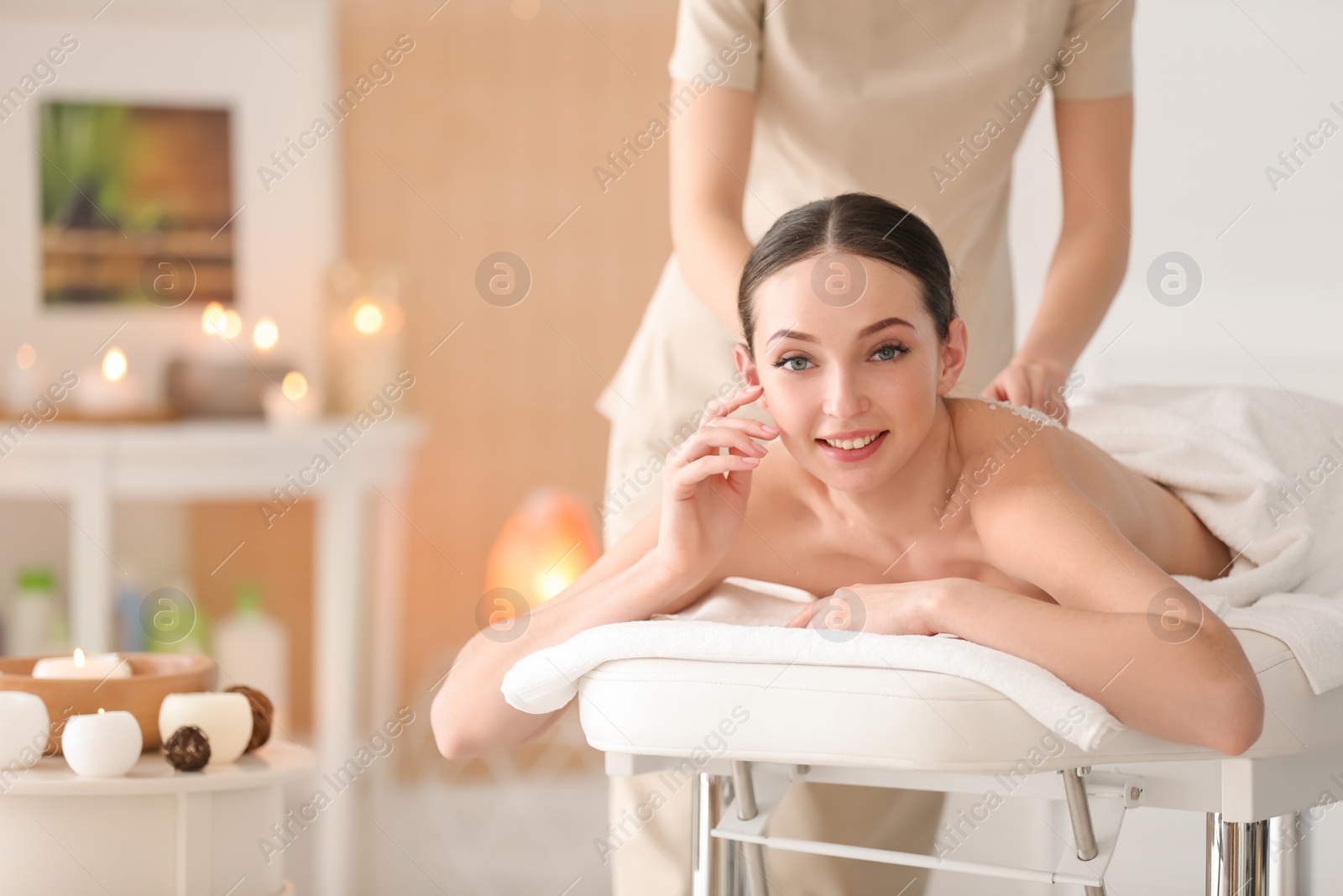 Photo of Beautiful young woman having massage with body scrub in spa salon