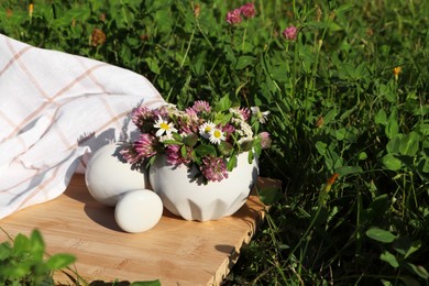 Photo of Ceramic mortar with pestle, different wildflowers and herbs on green grass outdoors. Space for text