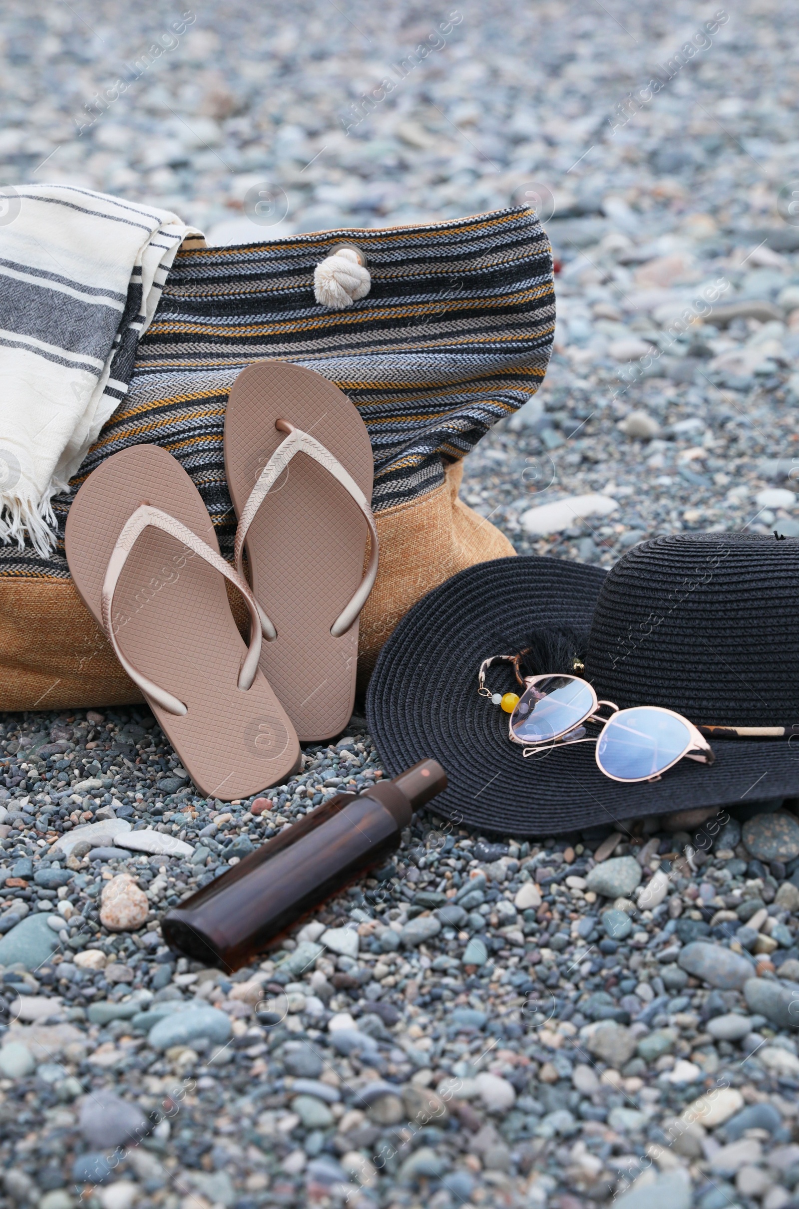 Photo of Set of different stylish beach accessories on pebble seashore