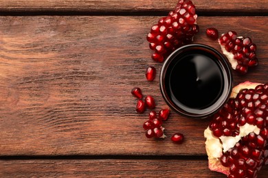 Glass bowl of tasty pomegranate sauce and fresh ripe fruit on wooden table, flat lay. Space for text