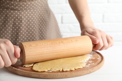 Photo of Making shortcrust pastry. Woman rolling raw dough at white wooden table, closeup