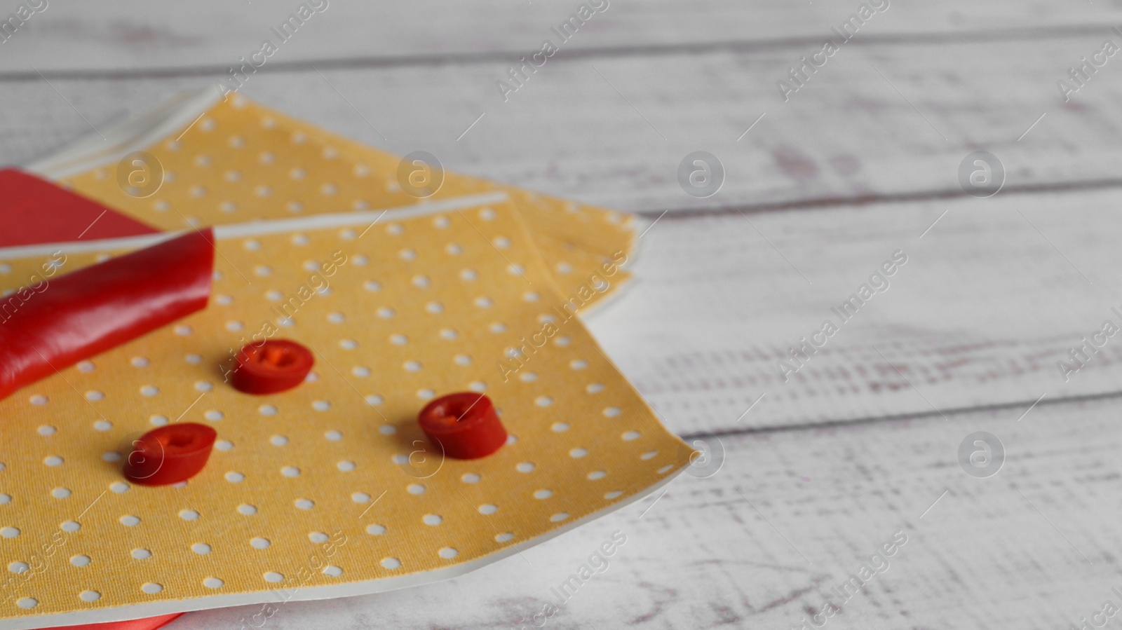 Photo of Many pepper plasters and chili on white wooden table, closeup. Space for text