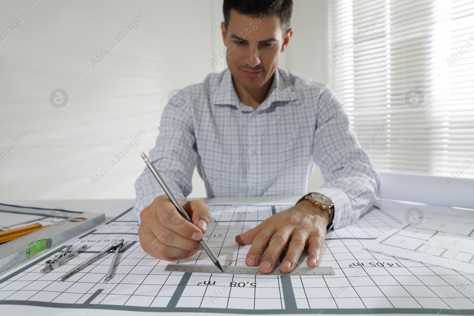 Photo of Architect working with construction drawings in office